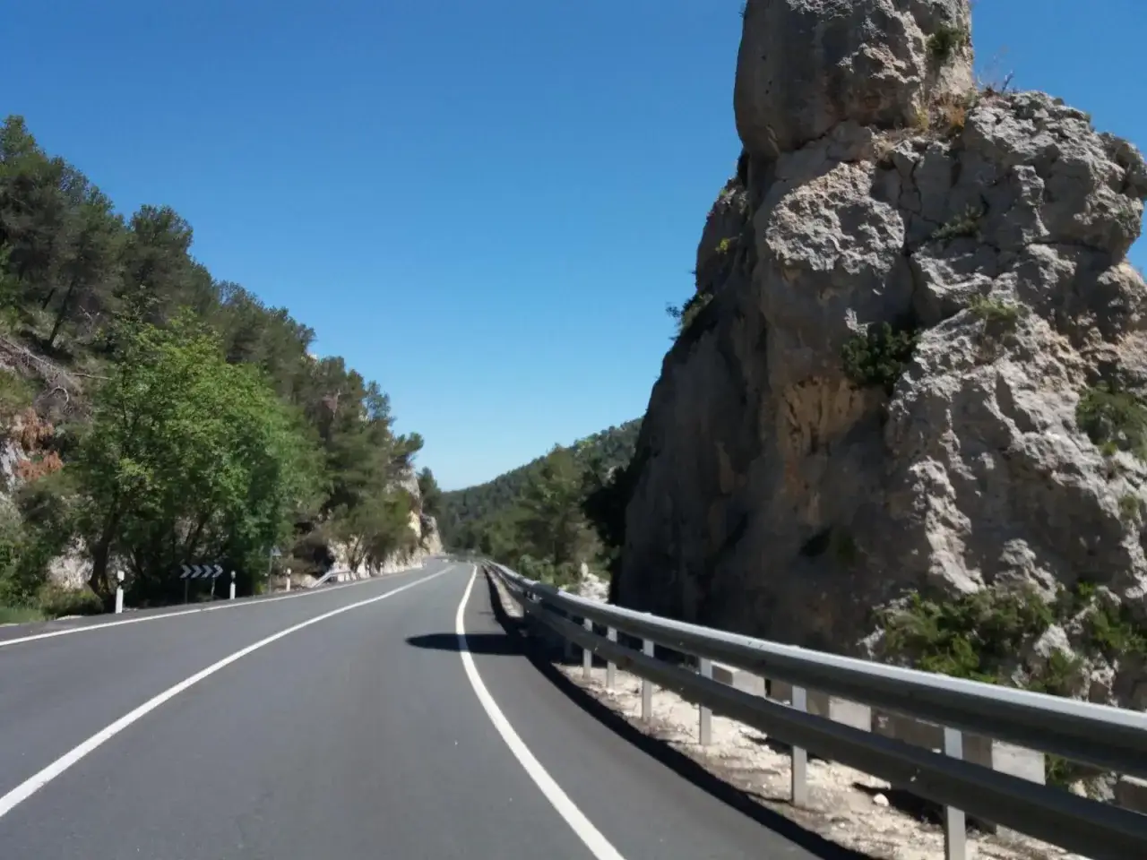 Carretera escénica con rocas imponentes y vegetación, ideal para tu viaje a Benilloba.
