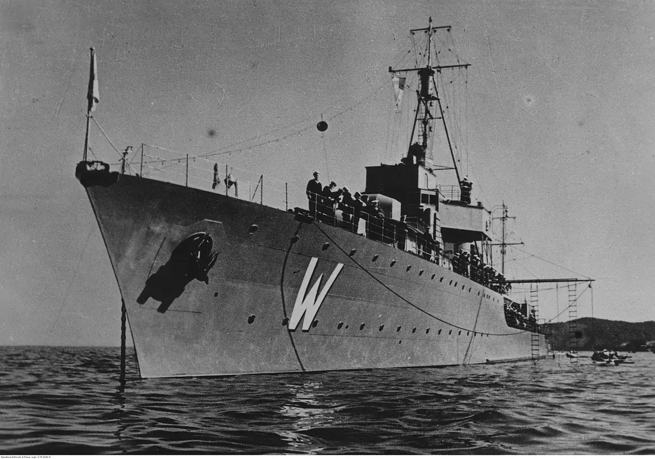 ORP Wicher, polski okręt wojenny, cumuje na spokojnych wodach. Na pokładzie widać grupę marynarzy.