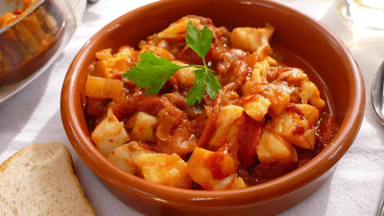 Un cuenco de barro con bacalao ajoarriero, un plato tradicional español, decorado con perejil.