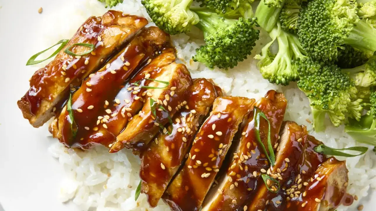 Pyszny kurczak teriyaki polany sosem, posypany sezamem, podany z ryżem i brokułami.