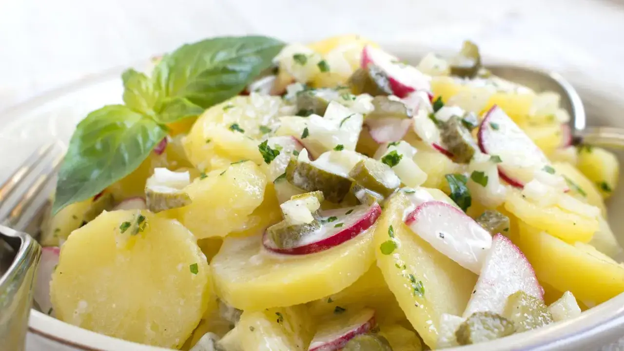Ein cremiger Kartoffel Radieschen Salat mit Gurken und frischen Kräutern, garniert mit Basilikum.