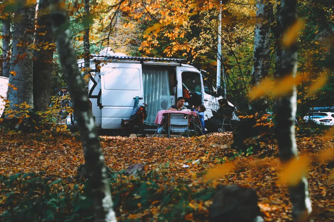 Familie genießt ihre **Herbstferien 2025 Schleswig-Holstein** im Wohnmobil, umgeben von bunten Blättern im Wald.