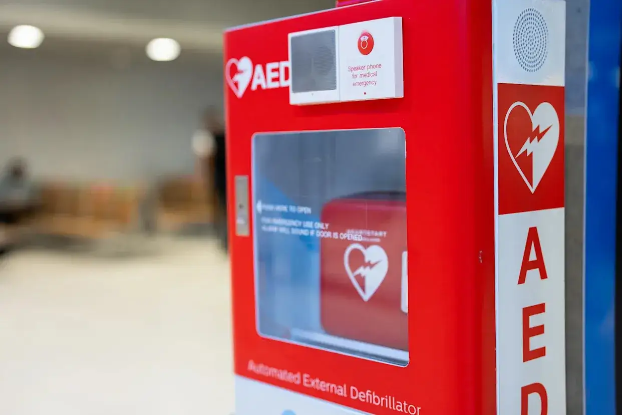 Czerwony defibrylator AED w miejscu publicznym, gotowy do użycia w nagłym wypadku.