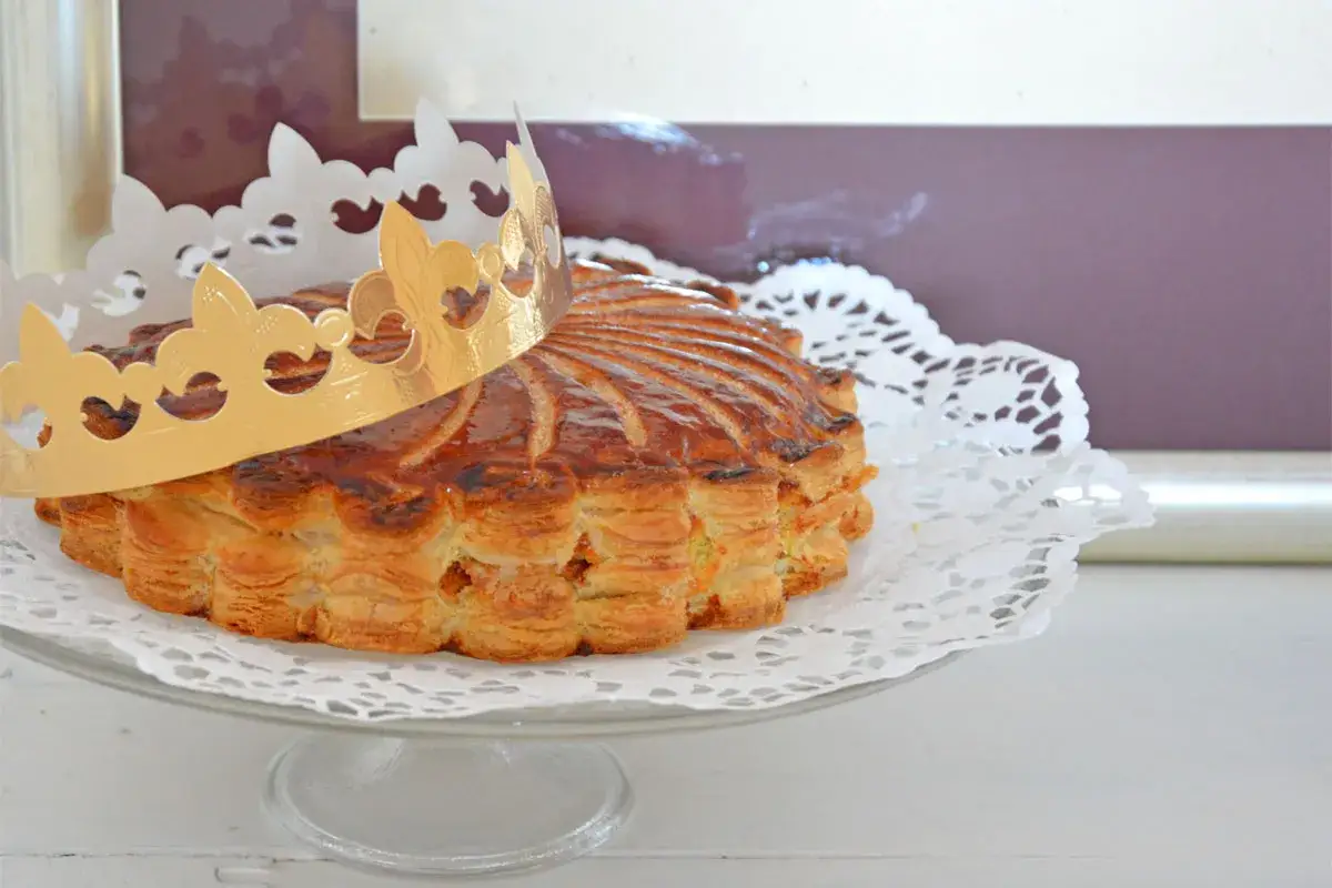 Goldene Krone auf einer k&ouml;stlichen Galette des Rois, bereit zum Teilen und Feiern.