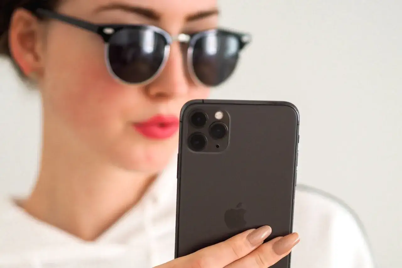 Dziewczyna w okularach przeciwsłonecznych robi selfie telefonem. Czy to aplikacja bereal co to?