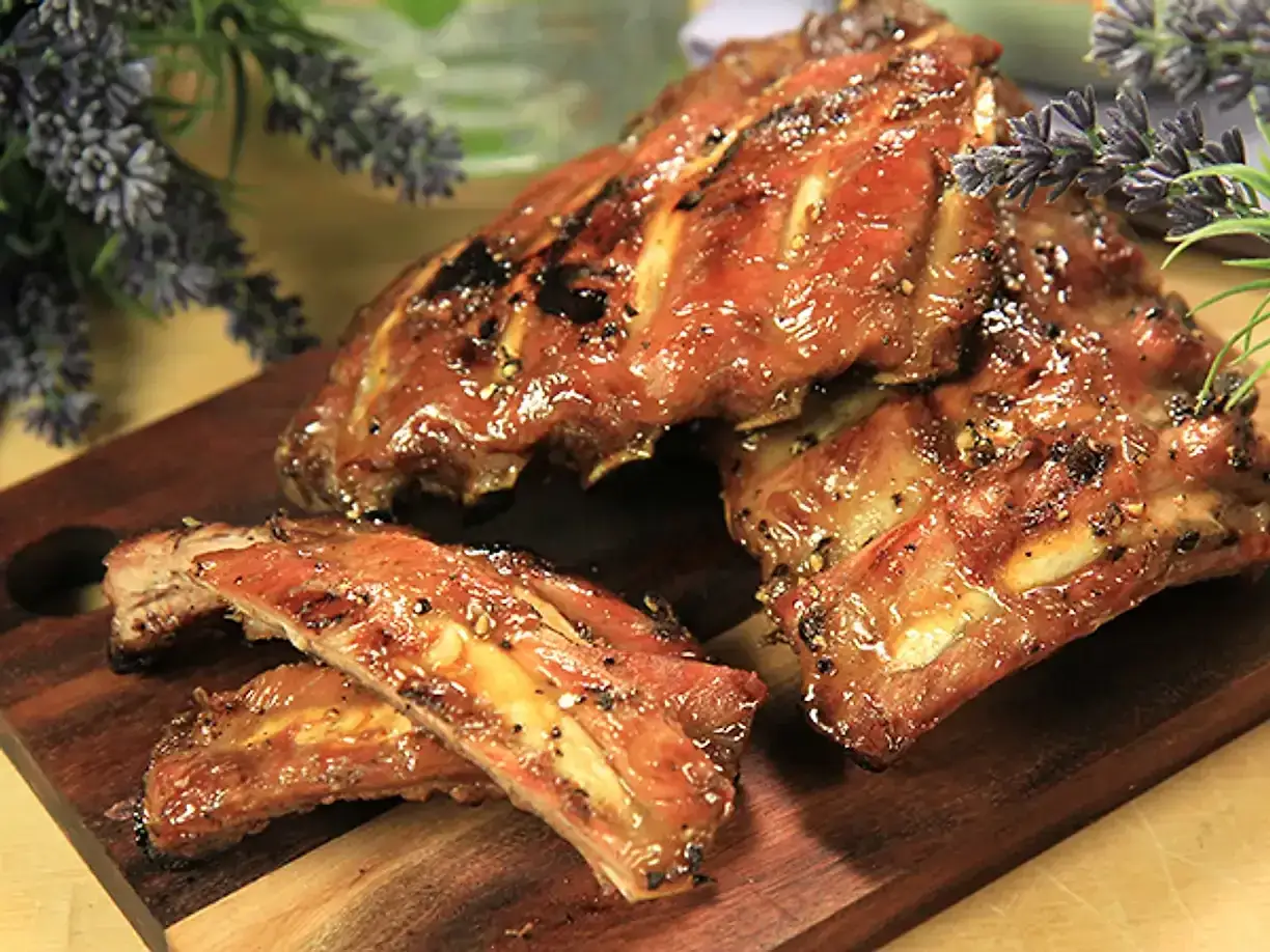 Saftiga kamben, perfekt grillade och glaserade, ligger upplagda på en träskärbräda. Doften av sommar och grillning sprider sig.