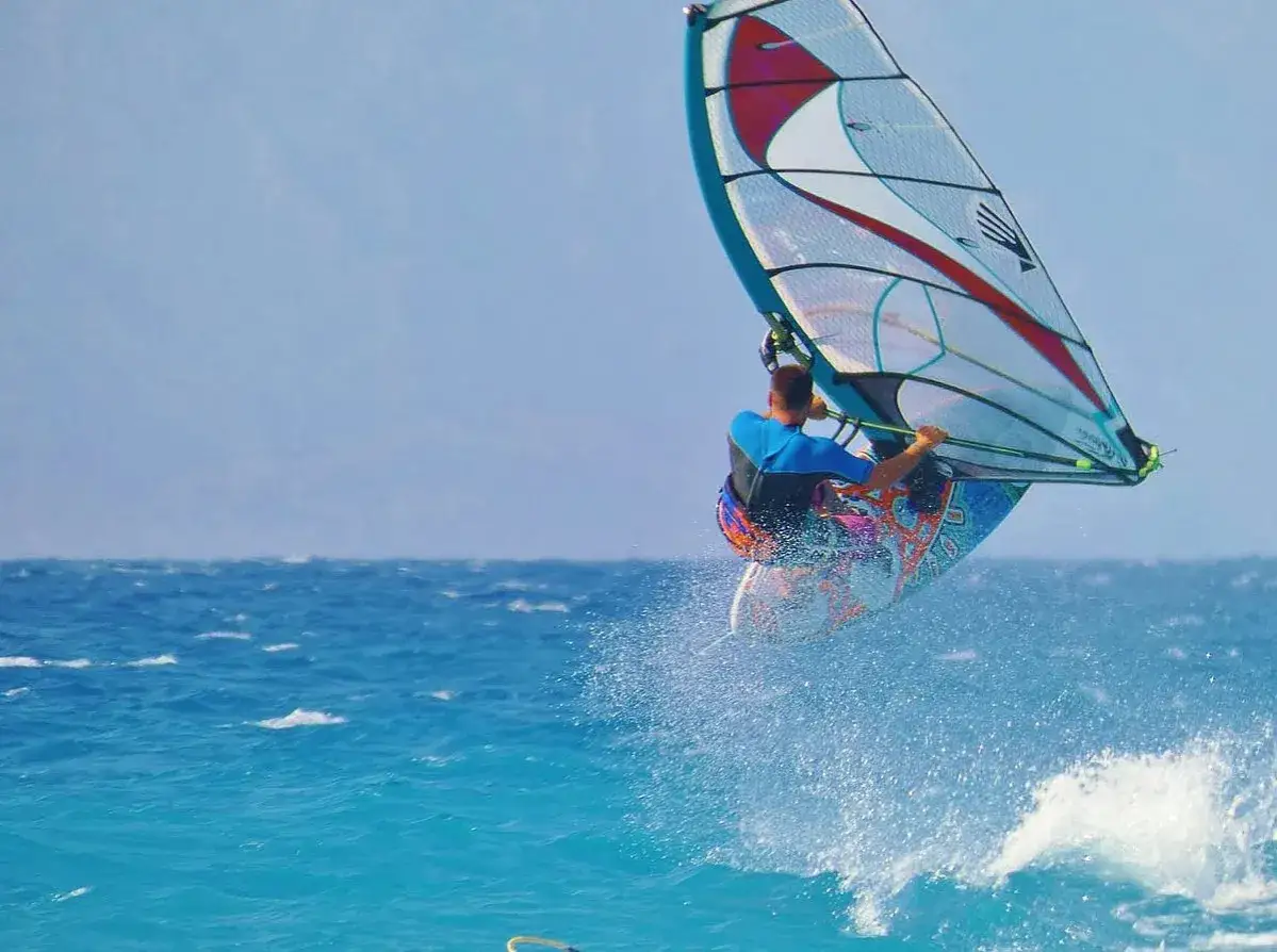 Ein Windsurfer springt hoch &uuml;ber dem t&uuml;rkisfarbenen Meer. Ein typischer Anblick beim Windsurfen Griechenland.
