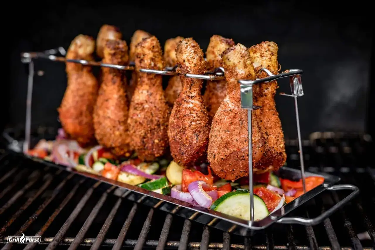 H&auml;hnchenschenkel in einer Gew&uuml;rzmischung f&uuml;r die **chicken wings marinade** ruhen auf einem Bett aus Gem&uuml;se auf dem Grill.