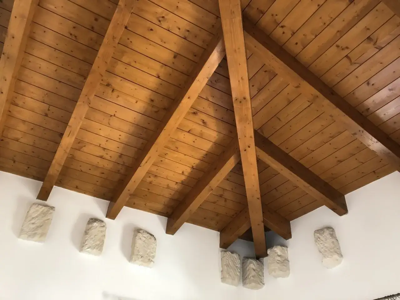 Soffitto con travi in legno a vista, evidenziando il trattamento delle travi in legno interne per un aspetto caldo e naturale.