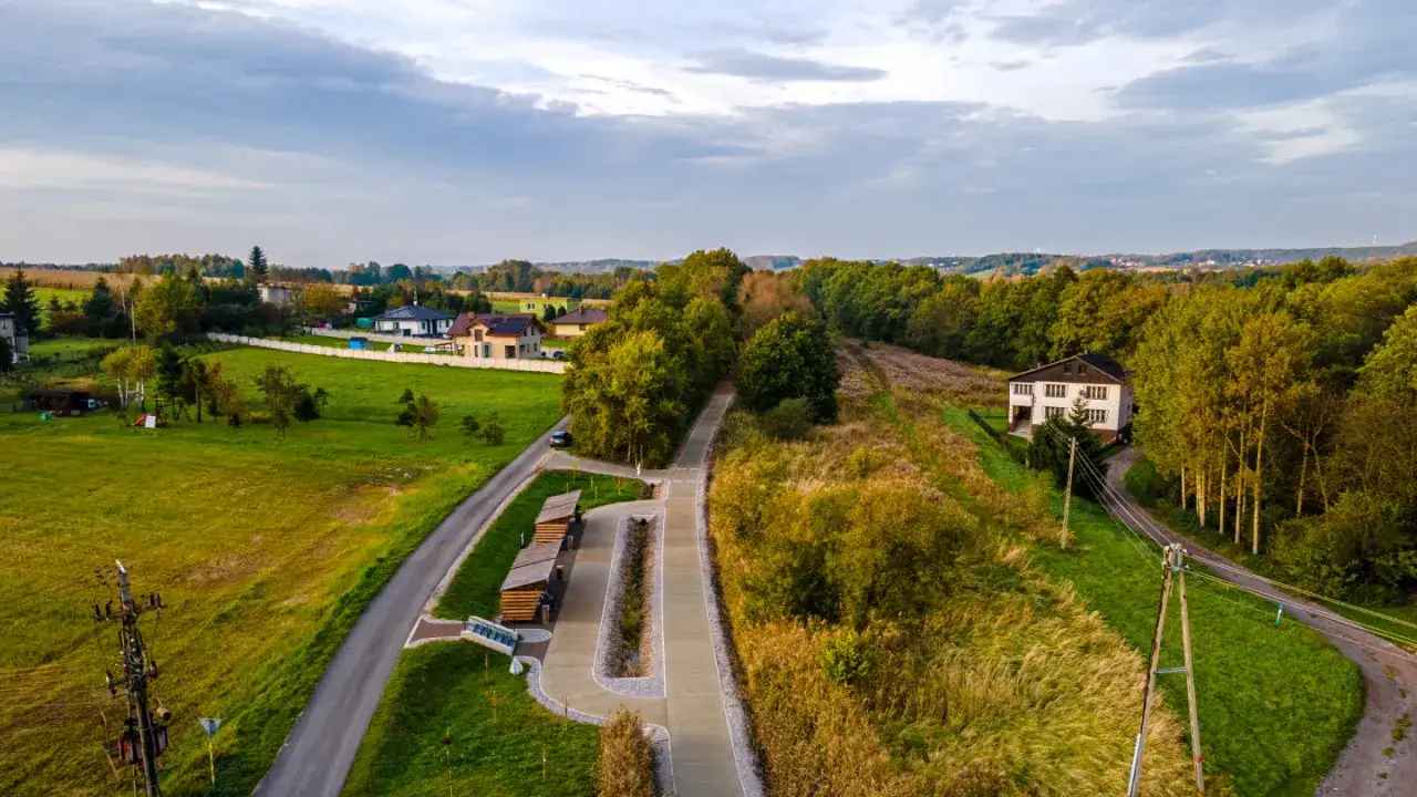 Malowniczy żelazny szlak rowerowy godów w otoczeniu zieleni i domów.