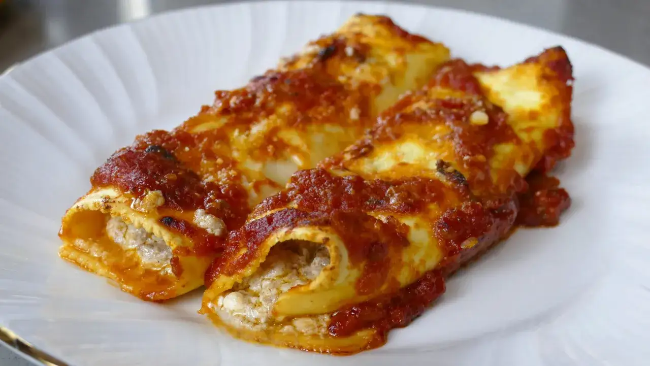 Due cannelloni di carne ripieni e ricoperti di sugo rosso, serviti su un piatto bianco.