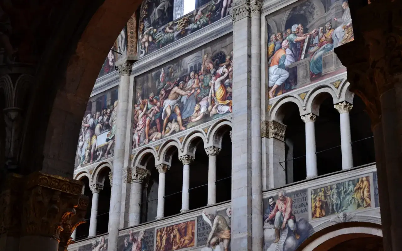 Affreschi di una citt&agrave; Emilia Romagna, scene bibliche su pareti di pietra, tra archi e colonne.