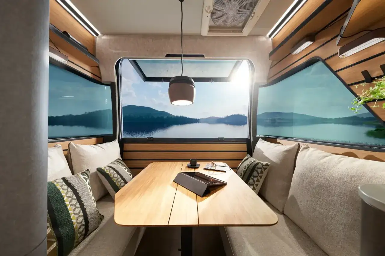 Mysig sittgrupp i en Hymer Venture S med fantastisk utsikt över en sjö och berg. Perfekt för avkoppling.
