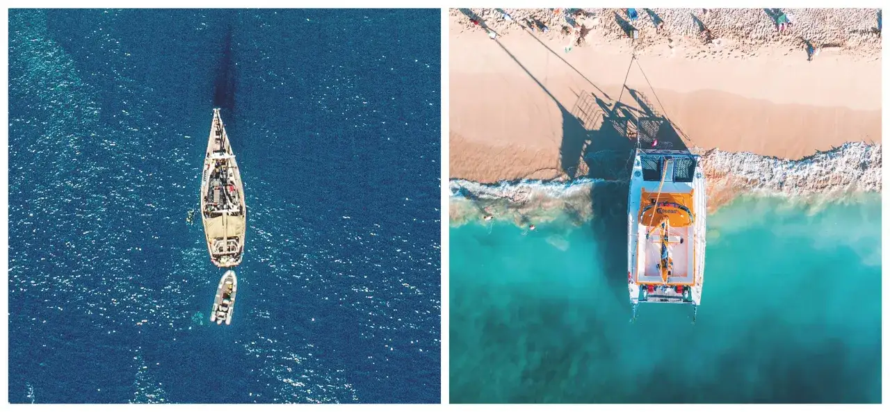 Il catamarano bianco e arancione &egrave; ormeggiato vicino a una spiaggia tropicale con persone che prendono il sole. Un altro catamarano pi&ugrave; piccolo &egrave; in mare aperto.