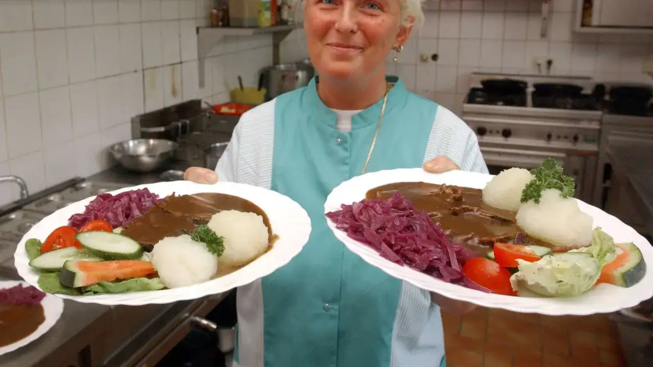 Zwei Teller mit original Sauerbraten, Klößen, Rotkohl und Salat.