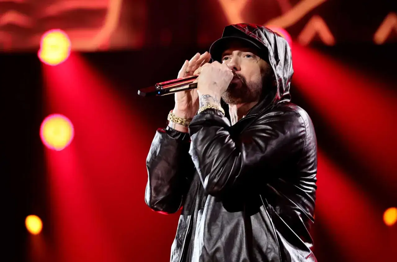 Eminem, raper znany z tego, że skąd pochodzi jego muzyka, występuje na scenie w sk&oacute;rzanej kurtce z kapturem.