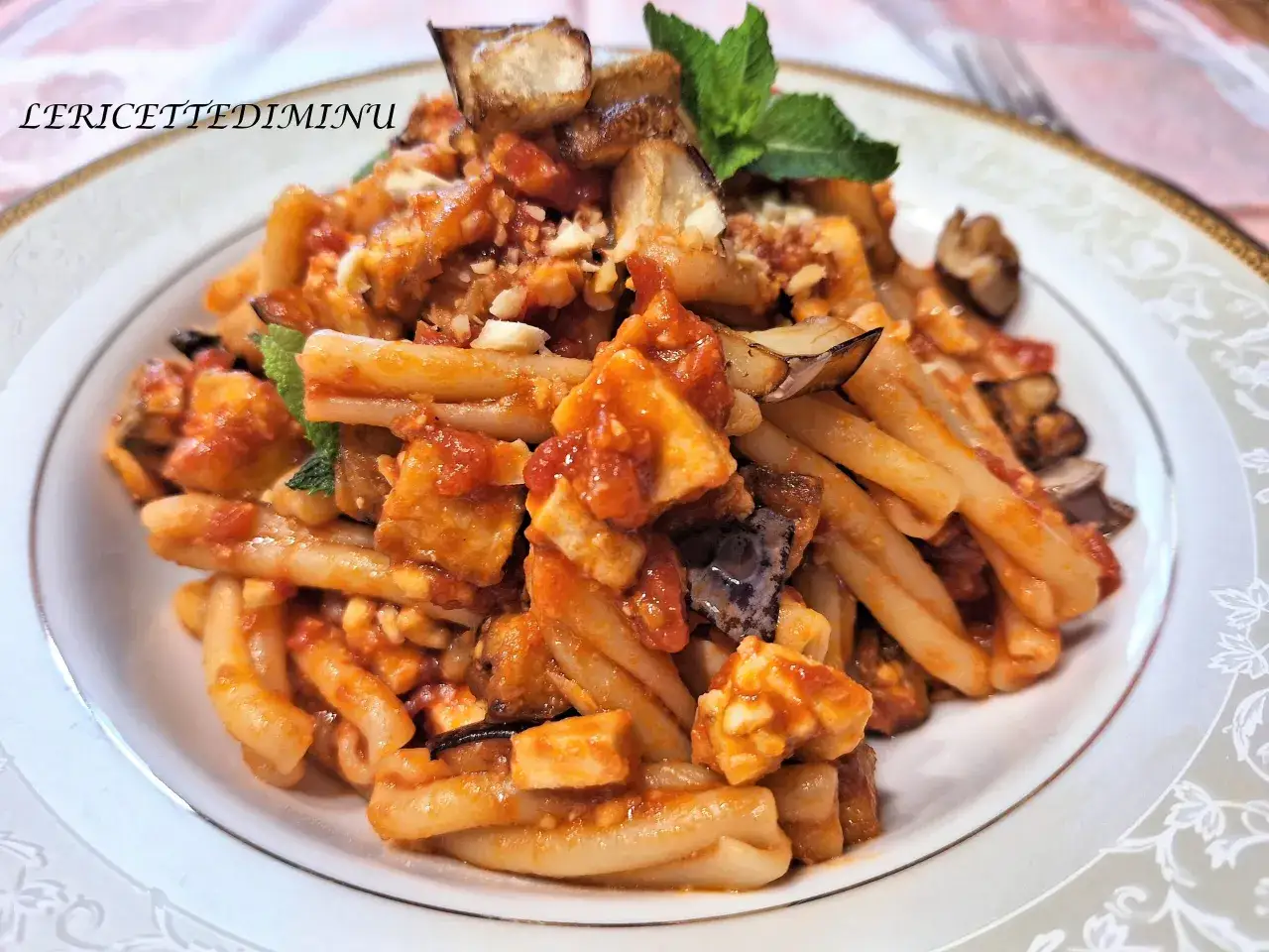 Pasta con pesce spada e melanzane, un piatto ricco di sapori mediterranei, guarnito con menta fresca.