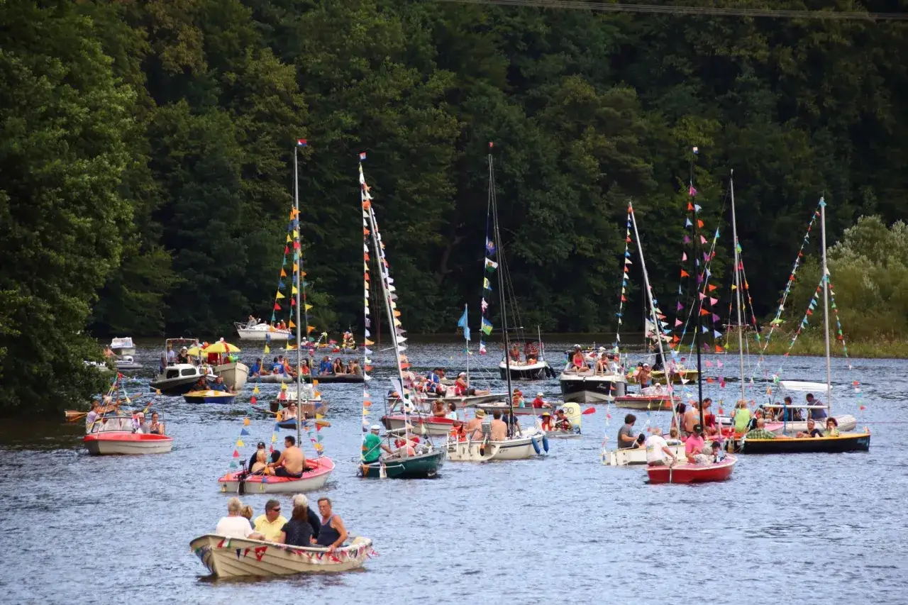 Bunte Boote und Segelschiffe mit Girlanden auf der Talsperre Kriebstein. Viele Menschen genie&szlig;en das sommerliche Baden und die Bootsfahrt.
