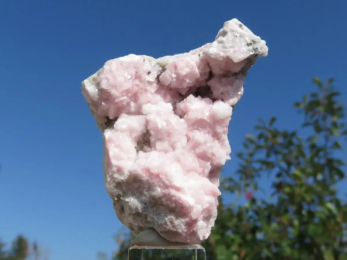 Roccia di rodocrosite rosa pallido, con cristalli aggregati su sfondo blu. Le sue propriet&agrave; sono legate all'amore e alla guarigione emotiva.