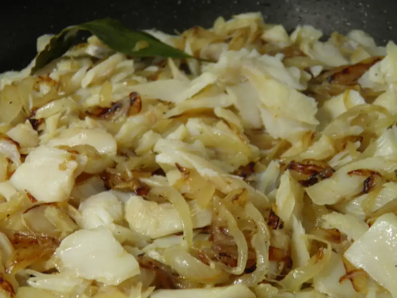 Morue à bras, un plat réconfortant de poisson effiloché et d'oignons caramélisés, avec une feuille de laurier.