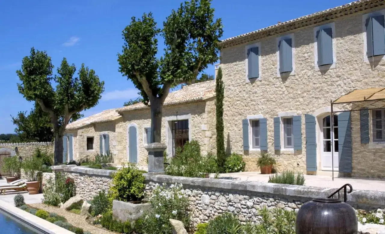 Maison ancienne en pierre avec volets bleus. Le jardin méditerranéen et la piscine invitent à la détente.