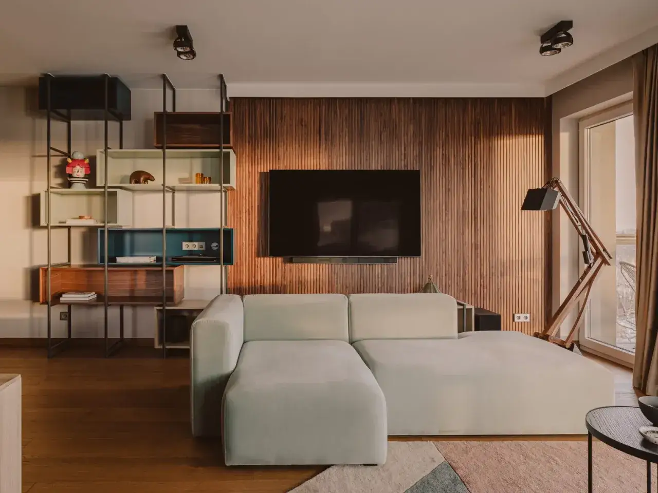 Nowoczesny salon z kanapą i telewizorem na ścianie z drewna. Zastanawiasz się, **fornir co to jest**? To cienki płat drewna, kt&oacute;ry nadaje wnętrzu ciepło i elegancję.