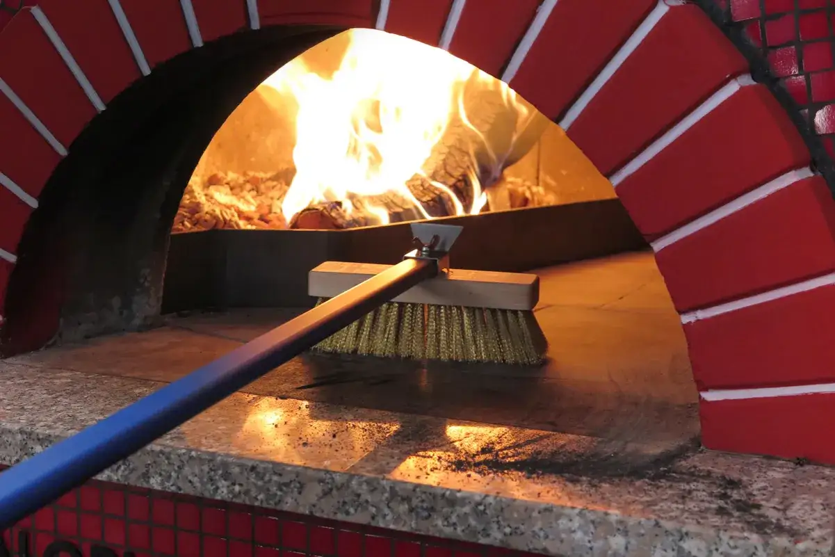 Spazzola in ottone per pulire il forno a legna, rimuovendo cenere e residui dopo l'uso.