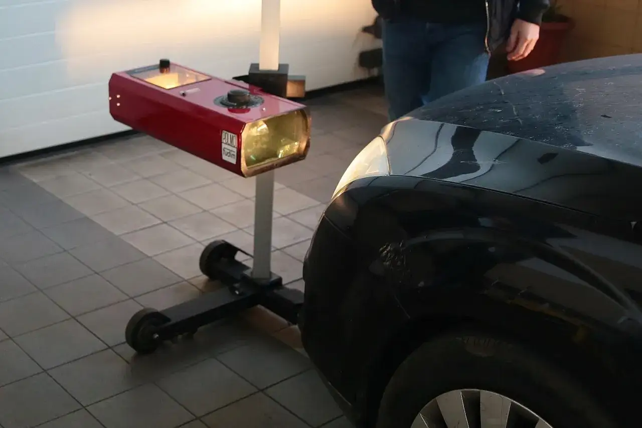 Urządzenie do ustawienia świateł 1 2 3 obok czarnego samochodu.