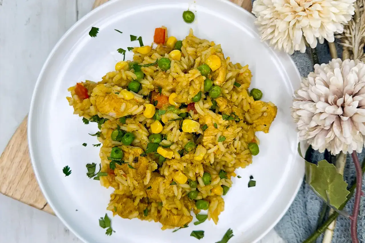 Un plato de arroz con pollo de la abuela, lleno de guisantes, maíz y trozos de pollo.