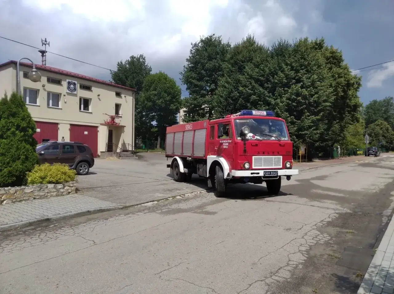 Czerwony wóz strażacki przed remizą. Czy straż pożarna usuwa gniazda os?