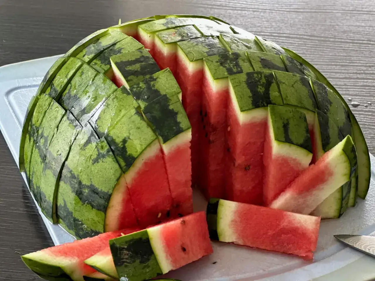 Eine Wassermelone richtig schneiden: So gelingt die perfekte Präsentation. Saftige rote Stücke auf einem Brett.