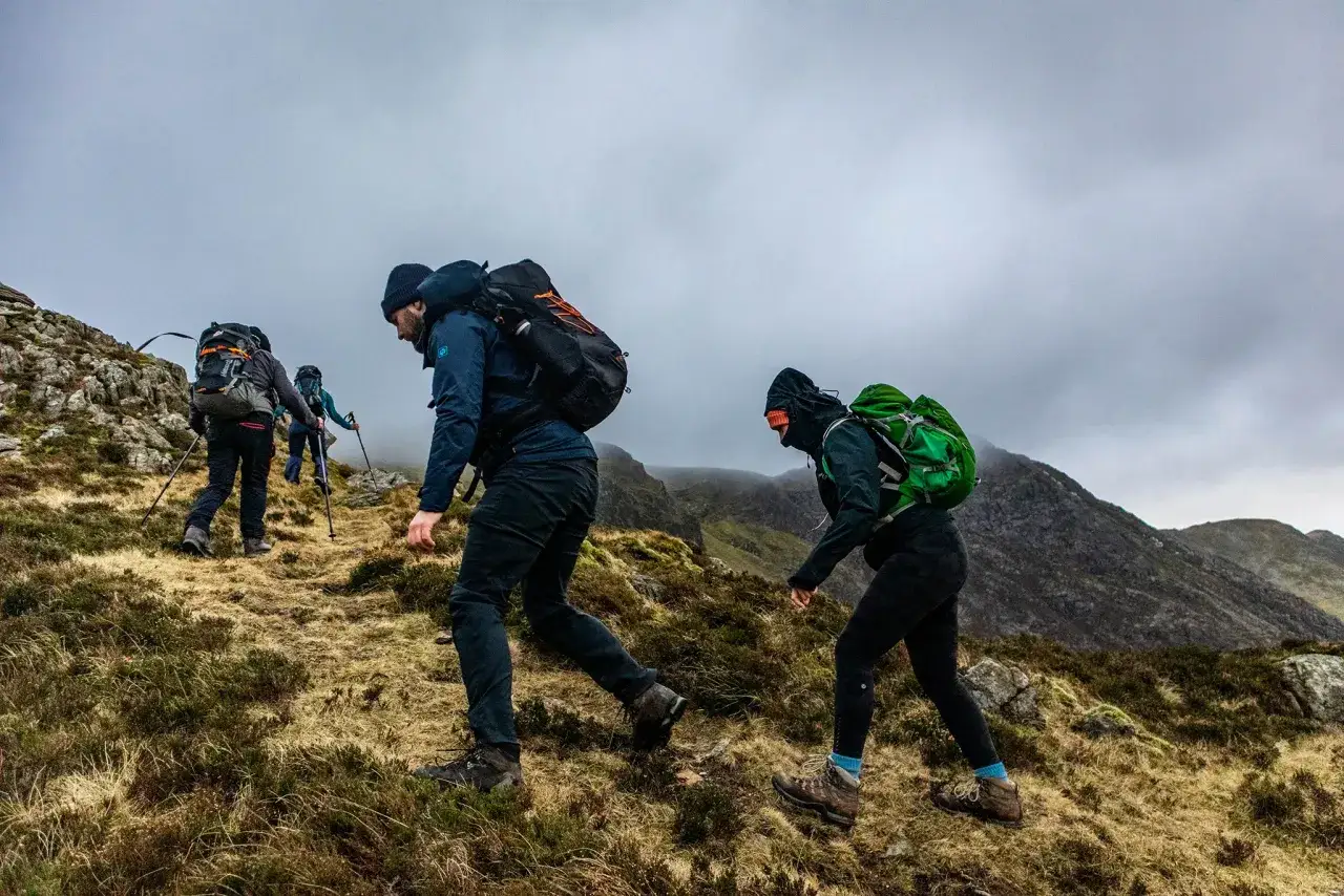 Grupa osób wyrusza na trekking. To wędrówka po górach, gdzie liczy się wytrwałość i piękno natury.