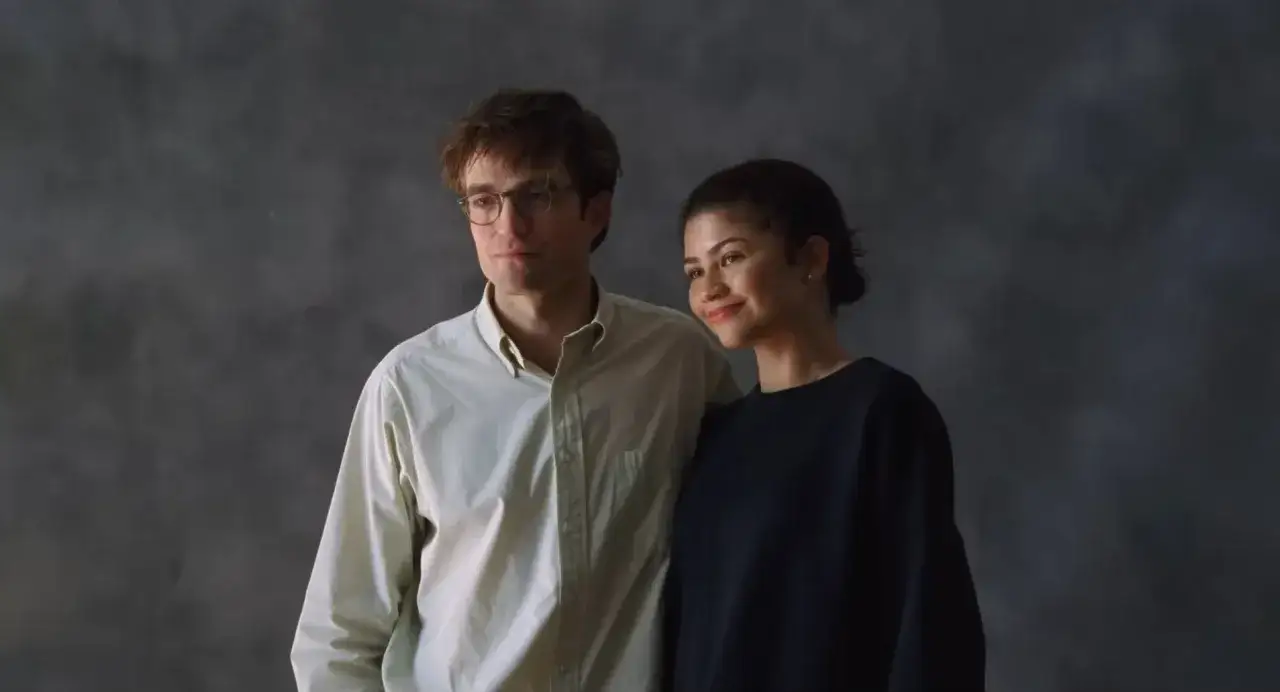 Un uomo con occhiali e una donna sorridono, vicini, in un'atmosfera che evoca il dramma del film.