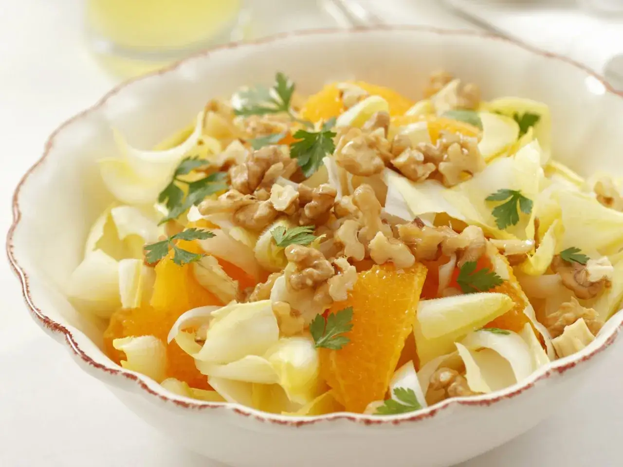 Erfrischender chicoree salat mit saftigen Orangenspalten, knackigen Walnüssen und Petersilie in einer Schüssel.
