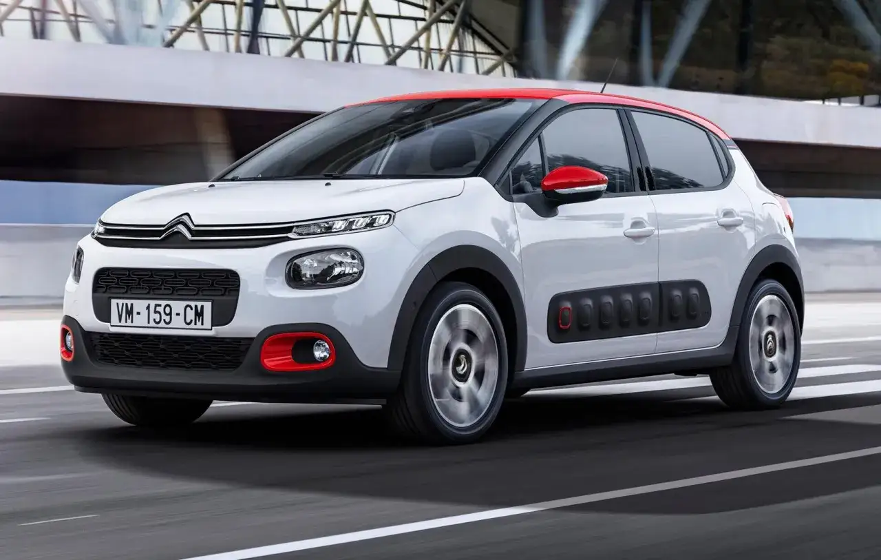 Biały Citroen C3 z czerwonym dachem i lusterkami, w ruchu. Niskie citroen c3 spalanie to jego atut.