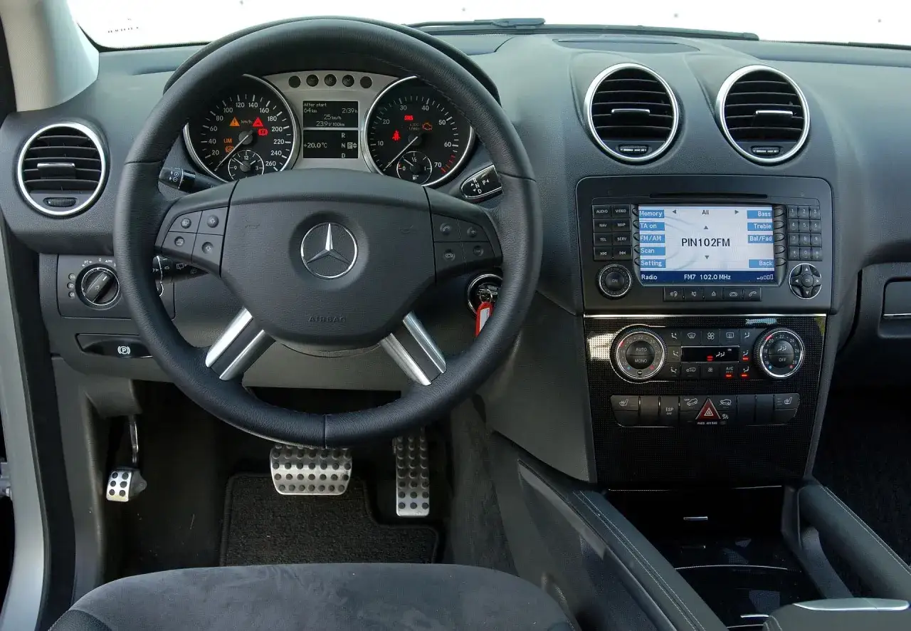 Wnętrze m class mercedes benz: kierownica, deska rozdzielcza z radiem i nawigacją, pedały.
