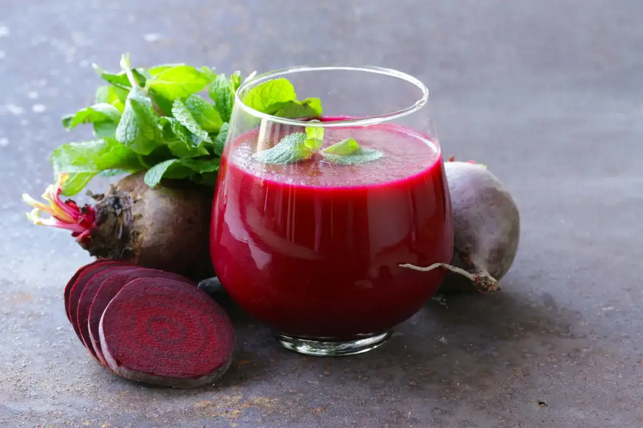 Vaso de zumo de remolacha con menta, acompañado de remolachas enteras y cortadas. Ideal como zumos para la anemia.