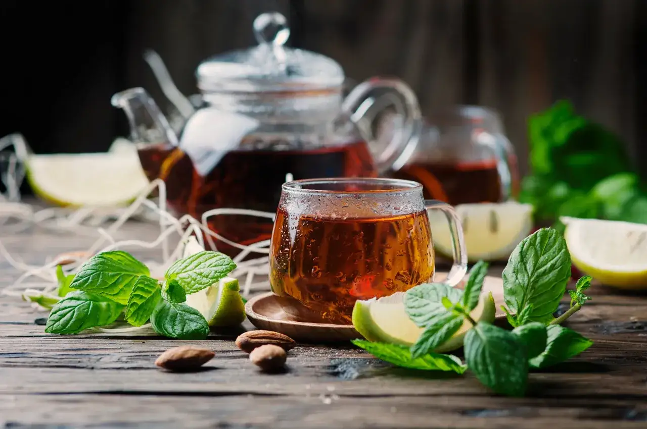 Aromatyczny napar z rooibos, parujący w szklance, z miętą i cytryną. Co to rooibos? To napój o bursztynowym kolorze, idealny na chłodne wieczory.