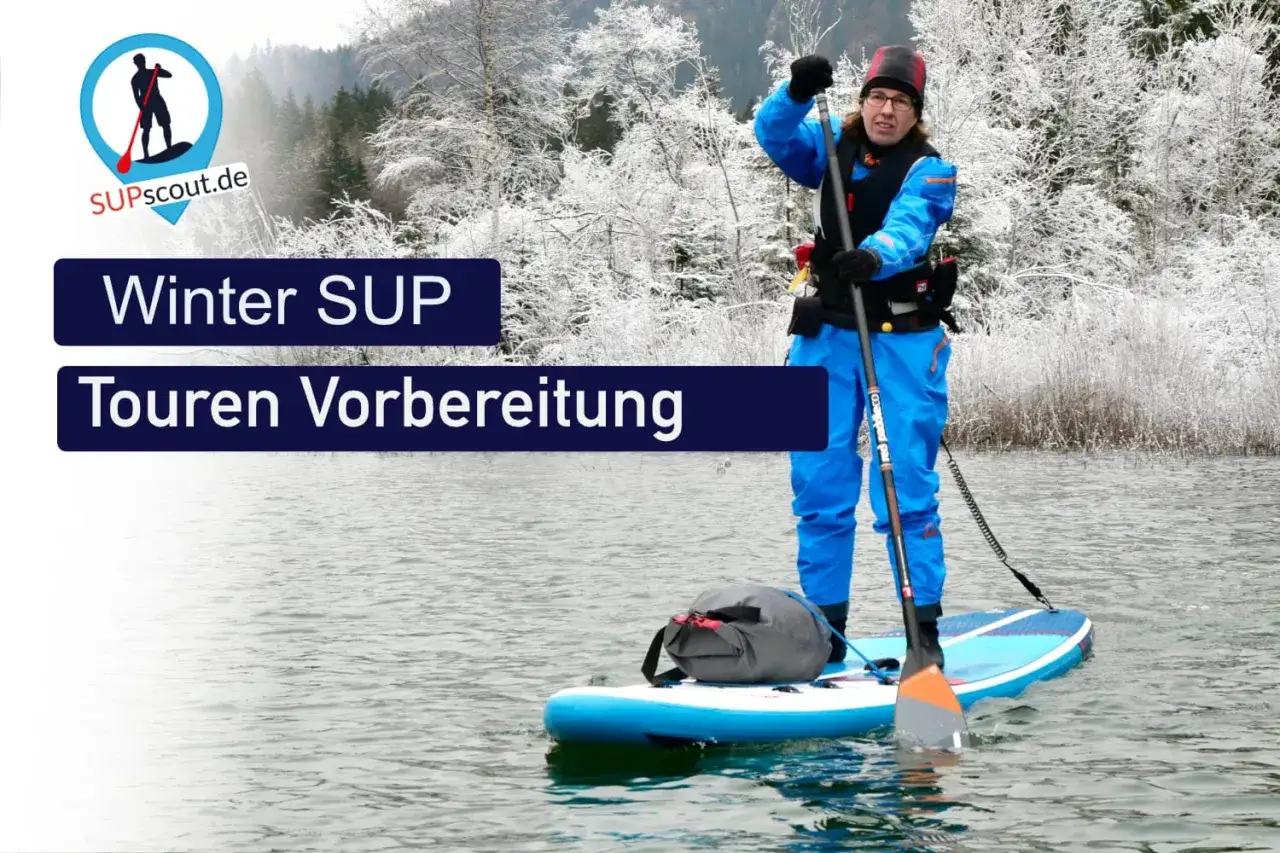 Person im blauen Neoprenanzug auf einem SUP-Board im Winter. Die Vorbereitung f&uuml;r eine Winter-SUP-Tour ist im Gange.