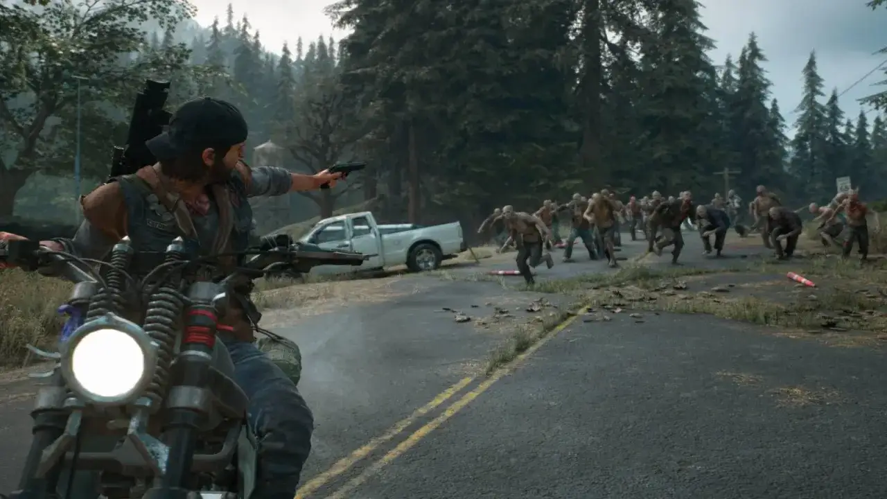 Motocyklista z bronią w ręku ucieka przed hordą zombie na drodze. To intensywny moment z gry Days Gone, gdzie każdy dzień to walka o przetrwanie.