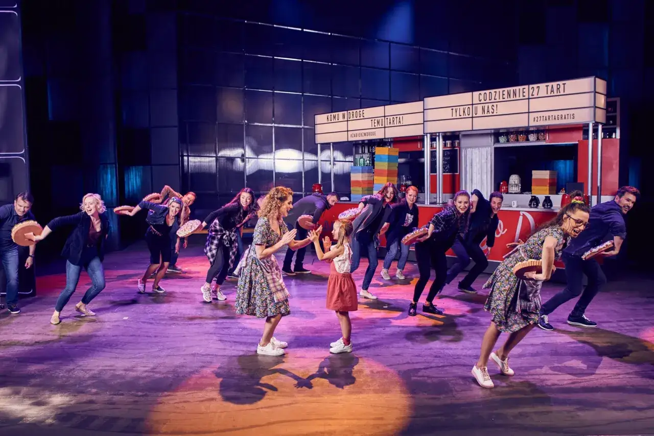 Scena z Teatru Roma. Aktorki w strojach kelnerek niosą tarty, tańcząc.