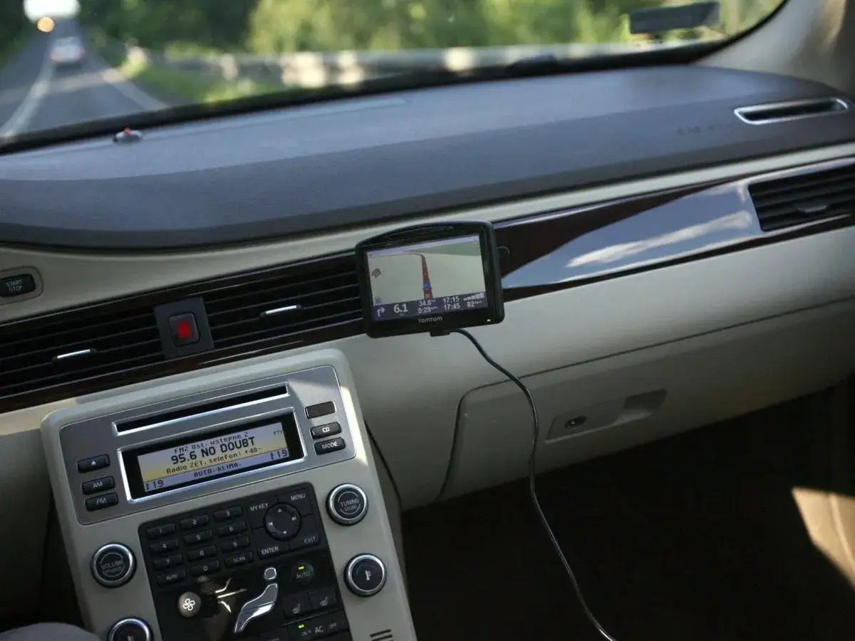 Nawigacja w telefonie pomaga kierowcy odnaleźć drogę. Na desce rozdzielczej widać ekran GPS z trasą.