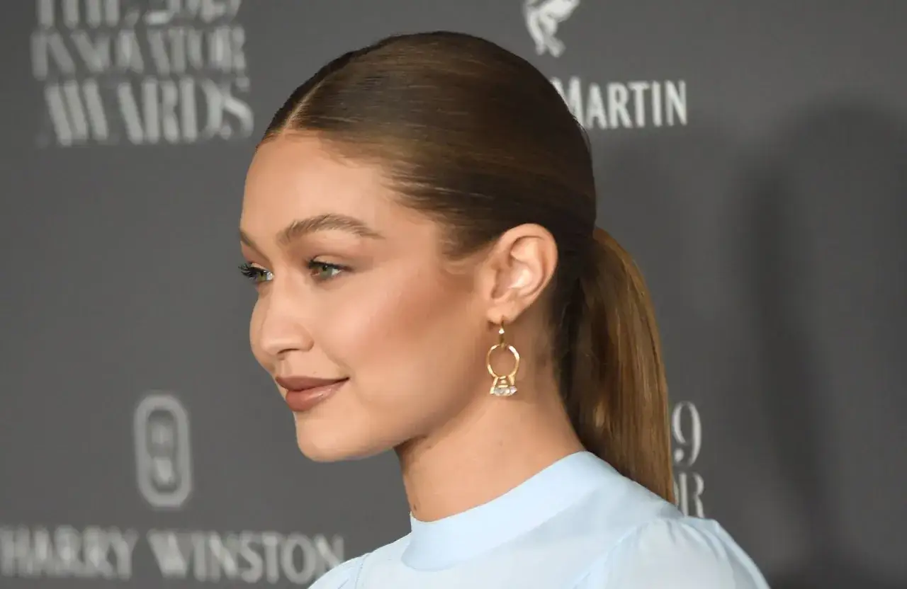 Gigi Hadid mit einem sleek Zopf und auffälligen Ohrringen, bereit für den roten Teppich.