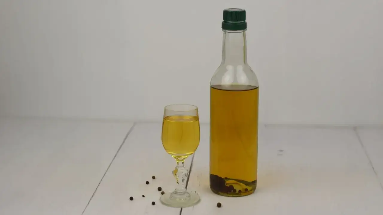 Domowa wódka pieprzowa na trawienie: jak zrobić, dawkowanie. Wódka z pieprzem w butelce i kieliszku, obok ziarna pieprzu.