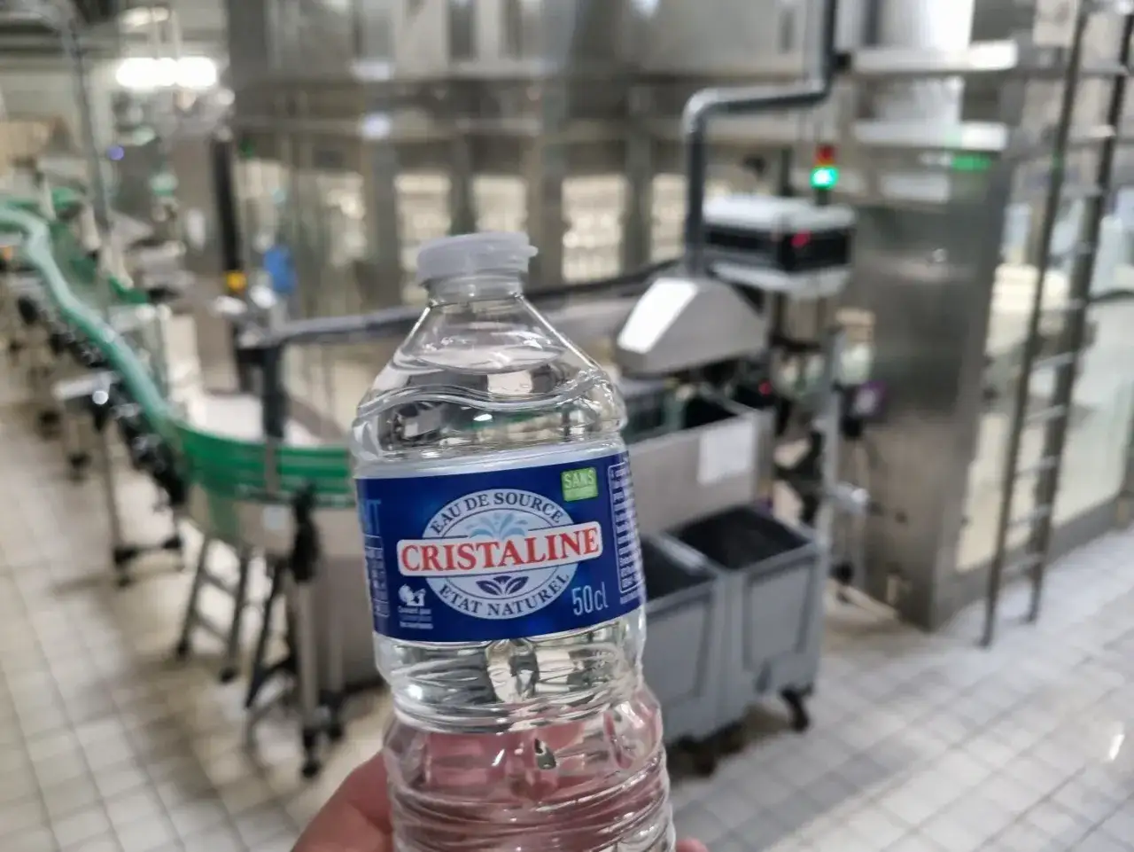 Une bouteille d'eau Cristaline dans une usine, rappelant le scandale eau en bouteille.