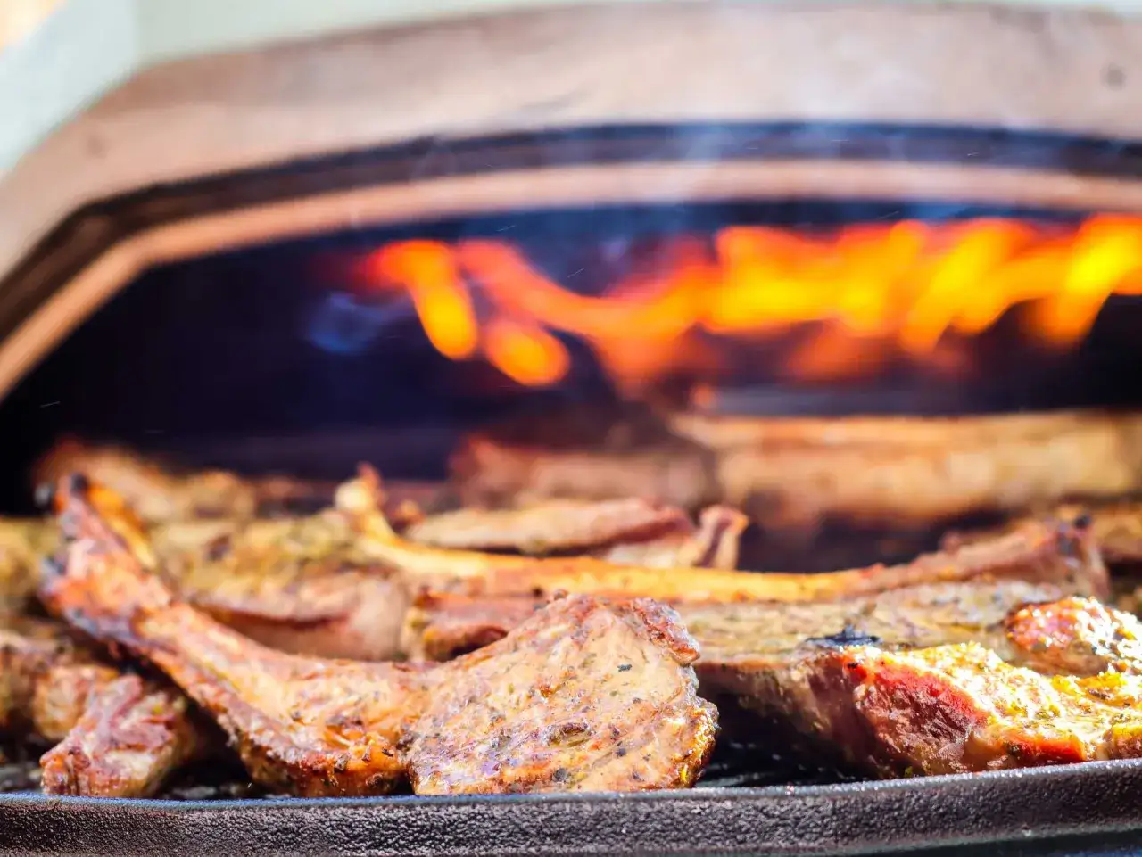 C&ocirc;tes d'agneau grill&eacute;es, savoureuses et juteuses, baignant dans une marinade parfum&eacute;e, avec des flammes vives en arri&egrave;re-plan.