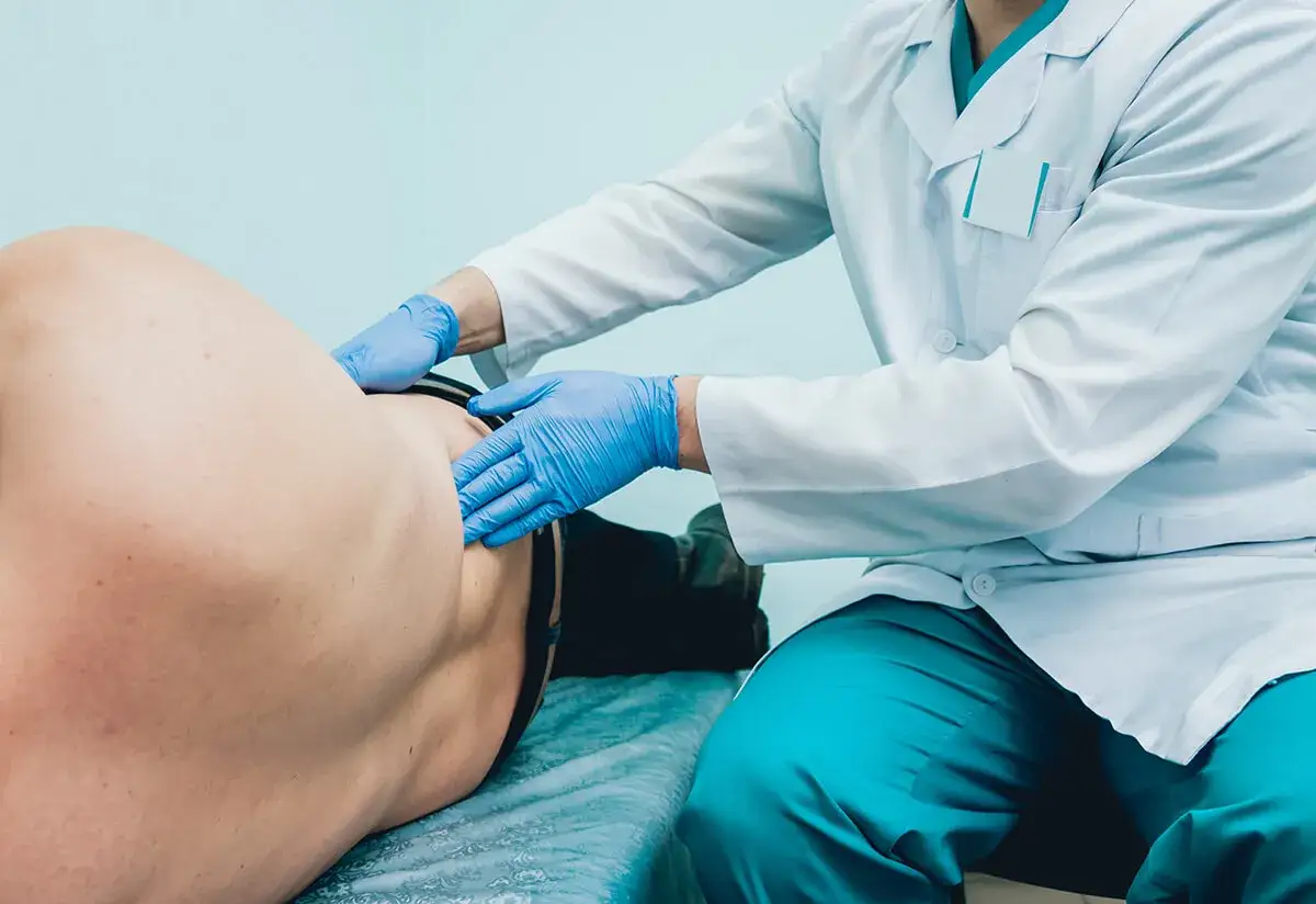 Urolog w rękawiczkach bada pacjenta. Zastanawiasz się, ile kosztuje wizyta u urologa prywatnie?