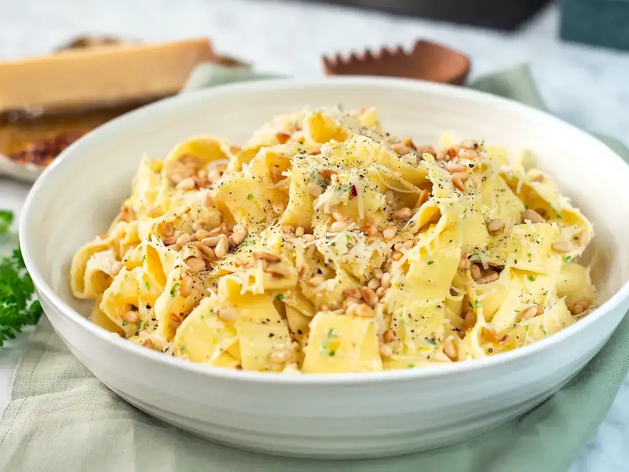 En skål med krämig pasta limone, toppad med pinjenötter och riven parmesan. Perfekt för en snabb och smakrik middag.