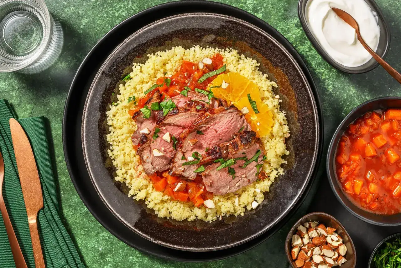 En härlig tallrik med marockansk mat: saftigt grillat kött på couscous med apelsin, tomatsås och mandlar.