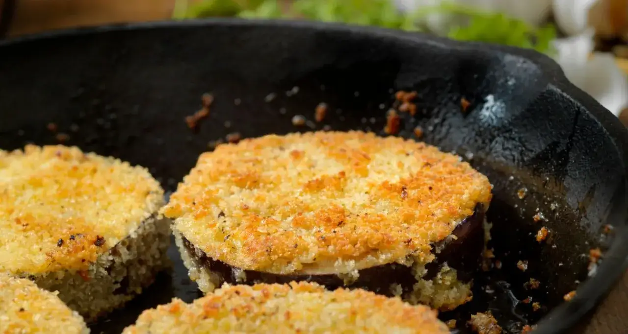 Fette di melanzane in padella, dorate e croccanti, con una panatura profumata al pangrattato.